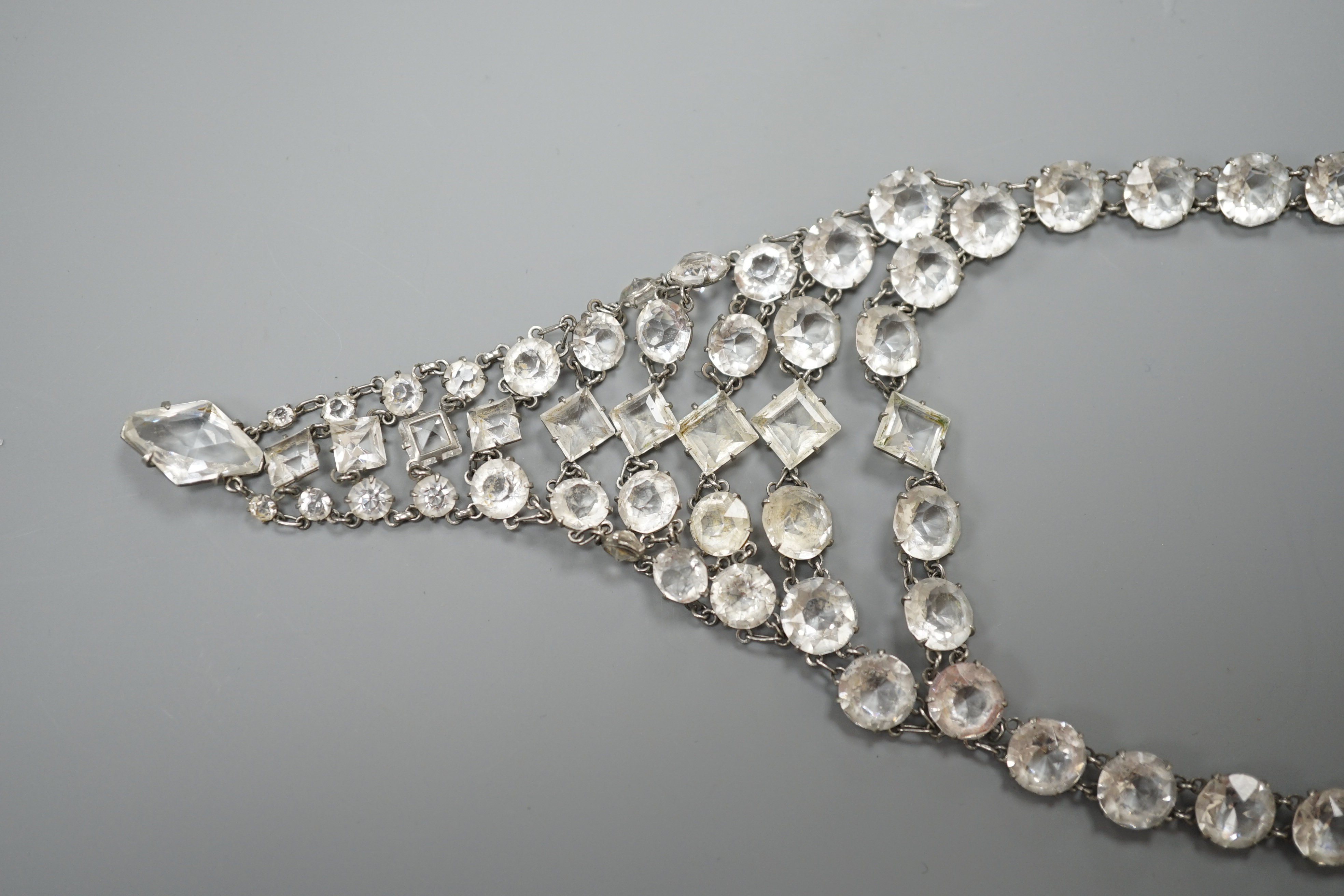 An early 20th century ornate white metal and facet cut paste set drop necklace, overall approx. 44cm.